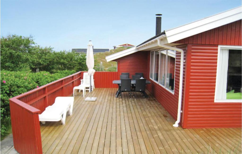 Casa roja con terraza con sillas y sombrilla en Martex, en Fanø