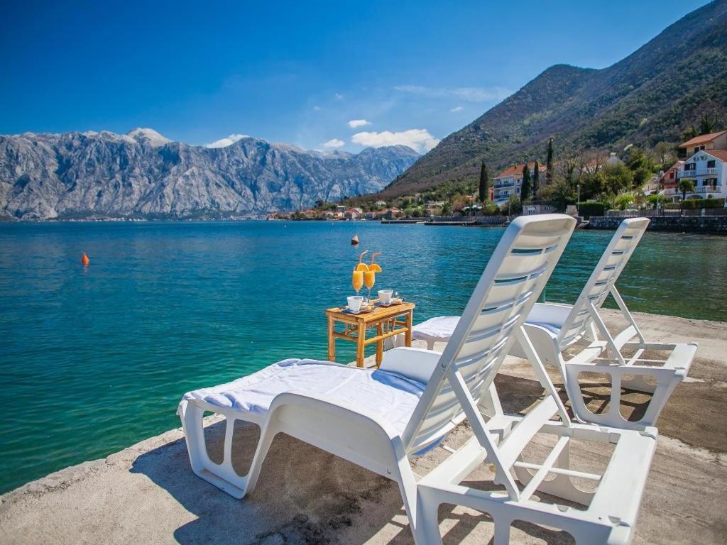 duas cadeiras brancas sentadas na margem de um lago em Daria Apartments em Kotor