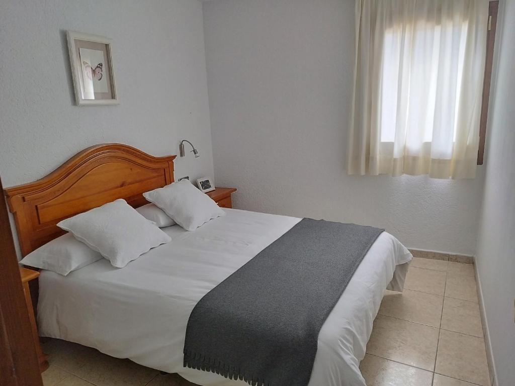 1 dormitorio con 1 cama con sábanas blancas y ventana en CAL JAN - SOLANA en Bellver de Cerdanya 
