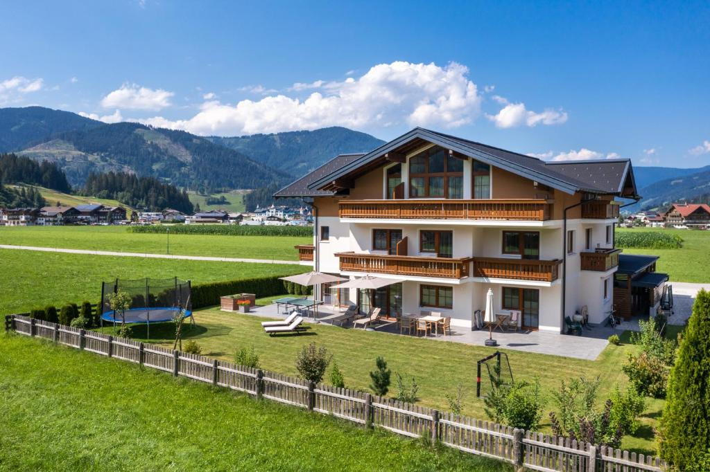 una casa in un campo con montagne sullo sfondo di Appartements Bergheimat a Flachau