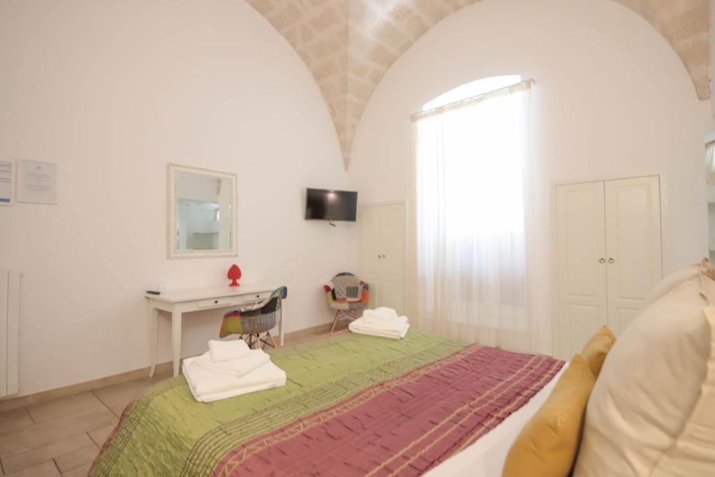 a bedroom with a bed and a desk and a window at Sogno D'Epoca 1822 in Monopoli