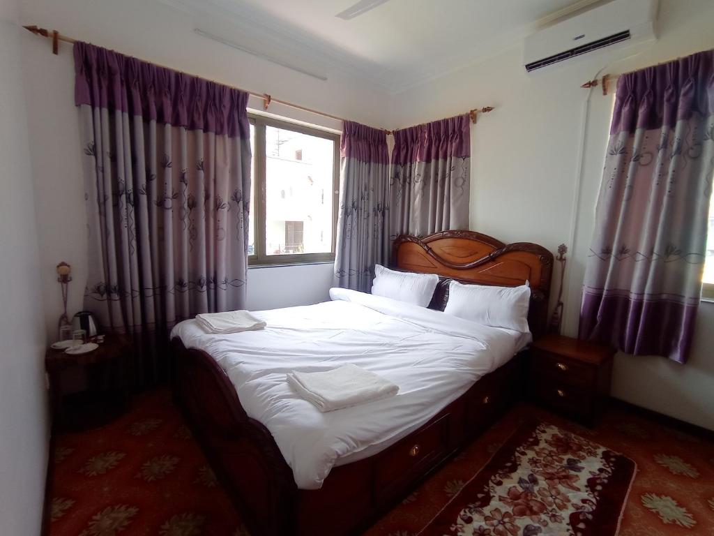 a bedroom with a bed with white sheets and a window at Janaki House in Kathmandu