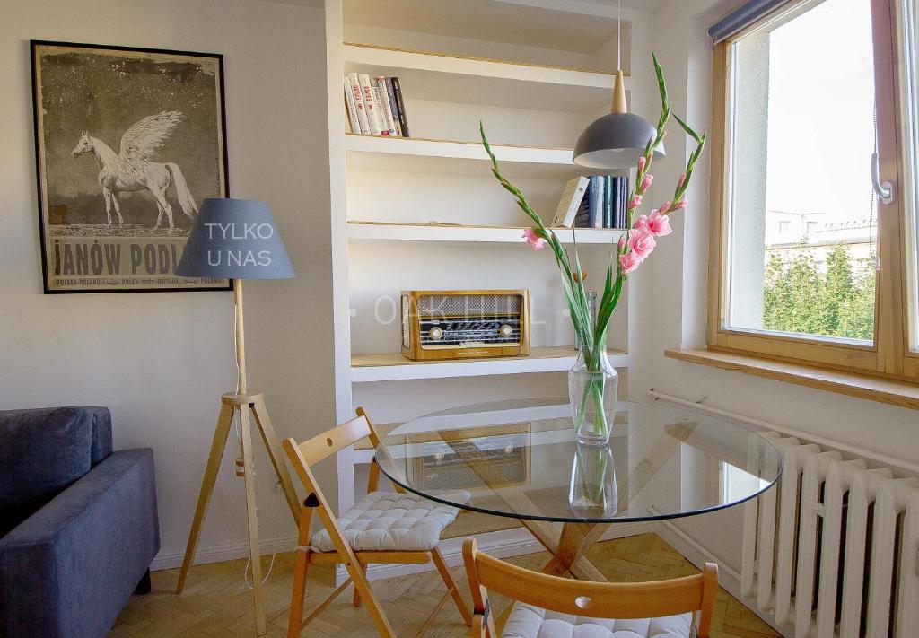 a living room with a glass table and a vase of flowers at Signe Home in Gdańsk