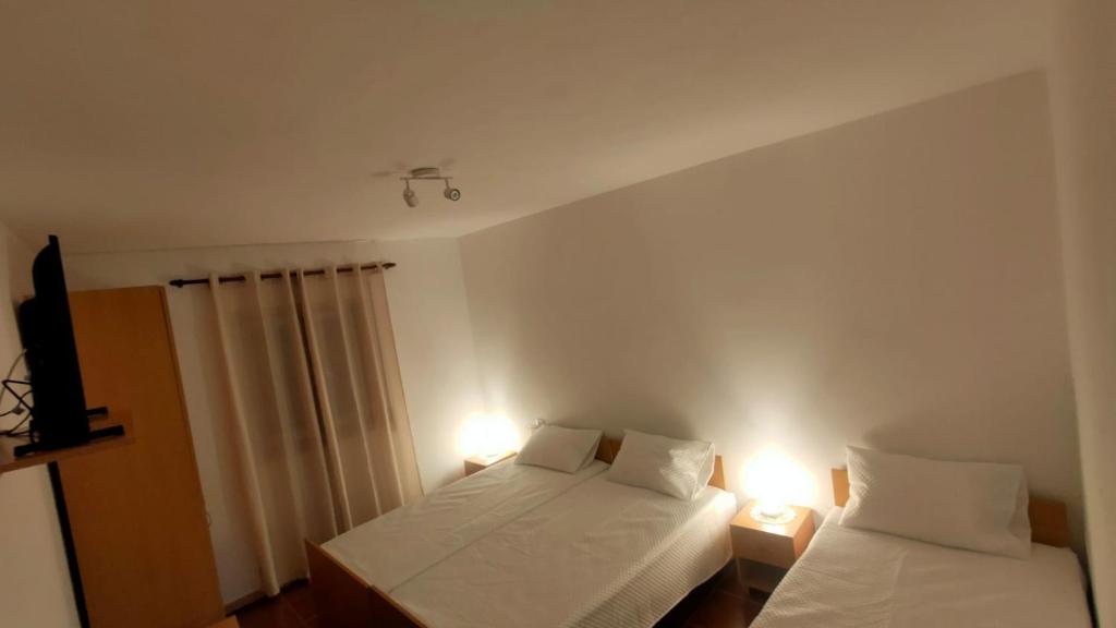 a bedroom with two beds and two lights on the wall at Casa da Clarinha in Castelo de Paiva