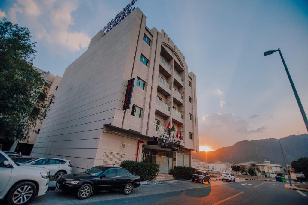 a building with cars parked in a parking lot at Sea Shore Hotel Apartment Khorfakkan in Khor Fakkan