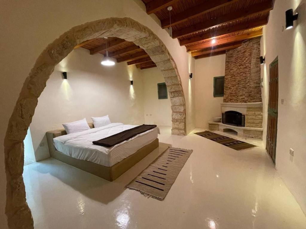 1 dormitorio con 1 cama en una habitación con un arco en Tafileh-Sila'a Heritage Village, en Tufailah
