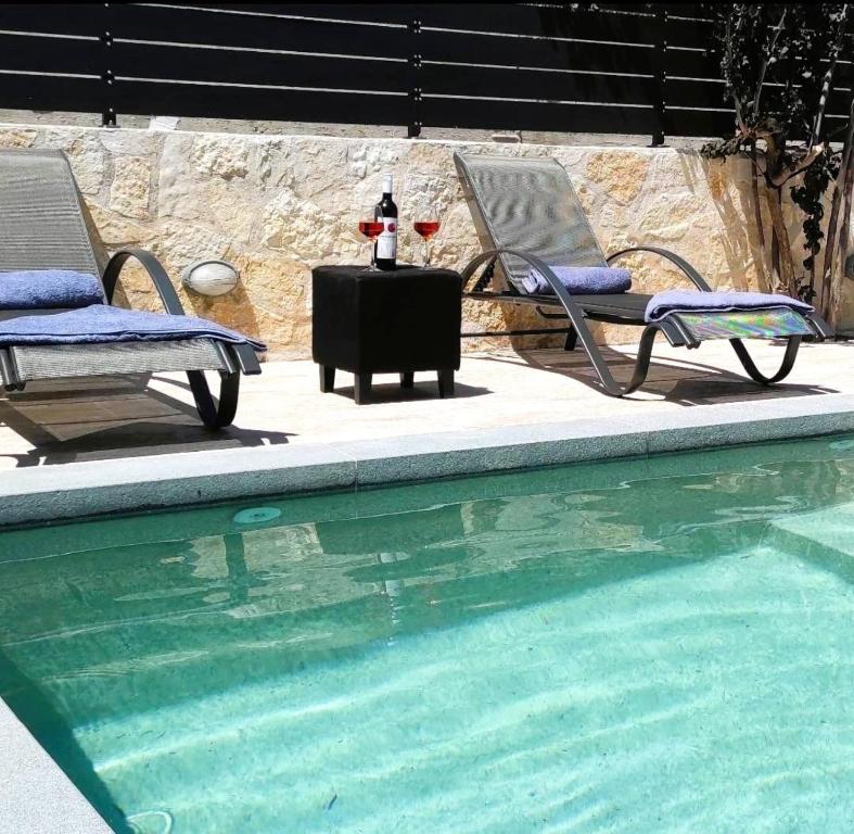 two chairs and a table next to a swimming pool at Villa Iliogioma with private pool and sea view in Katomérion