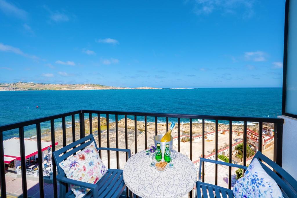 a table and chairs on a balcony with the ocean at Islet Promenade Seafront Family Apartment with 2 balconies by Getawaysmalta in St Paul's Bay