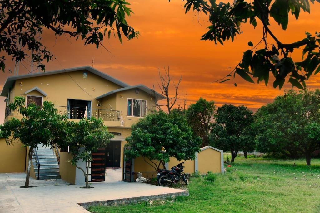 ラムナガルにあるCorbett wala by ayu villaの夕日を背景にした家