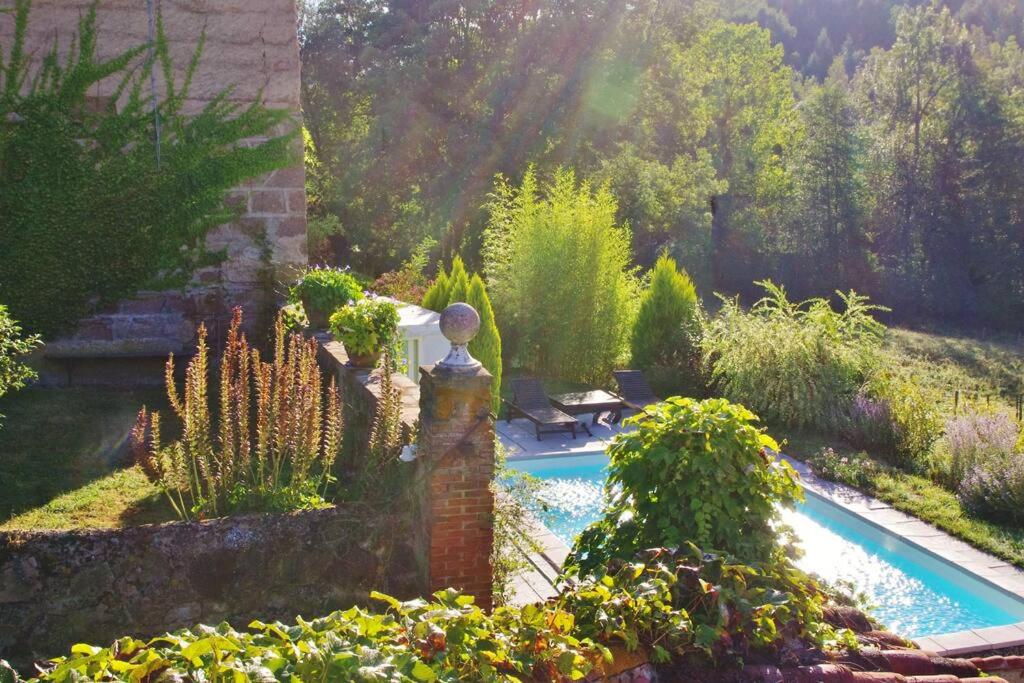 un jardin avec une piscine, une table et des fleurs dans l'établissement Nature calme piscine privée chauffée 7 jours minimum, à Brullioles