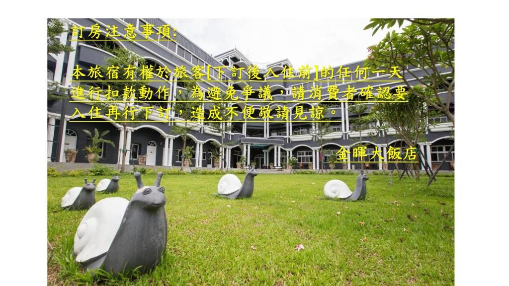 a group of birds sitting in the grass in front of a building at Jinhue Hotel in Luye