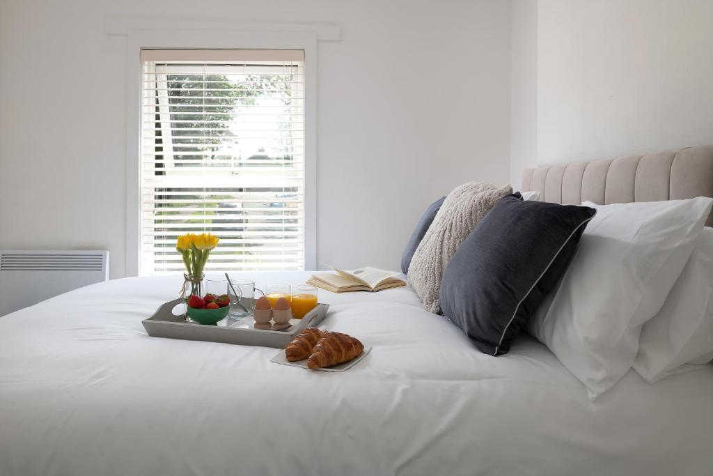 a tray of food on a bed with fruit and juice at Bron Eryri - Our Cosy House opposite the entrance to Portmeirion! in Mynfford