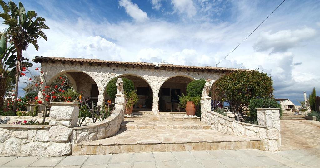 un edificio de piedra con escaleras y un arco en Oikos Selinolithos en Alaminos