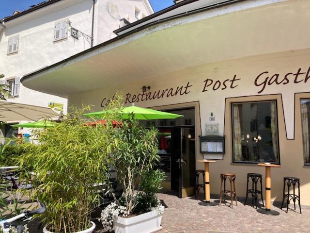 a restaurant with plants in front of a building at Gasthof zur Post in Egna