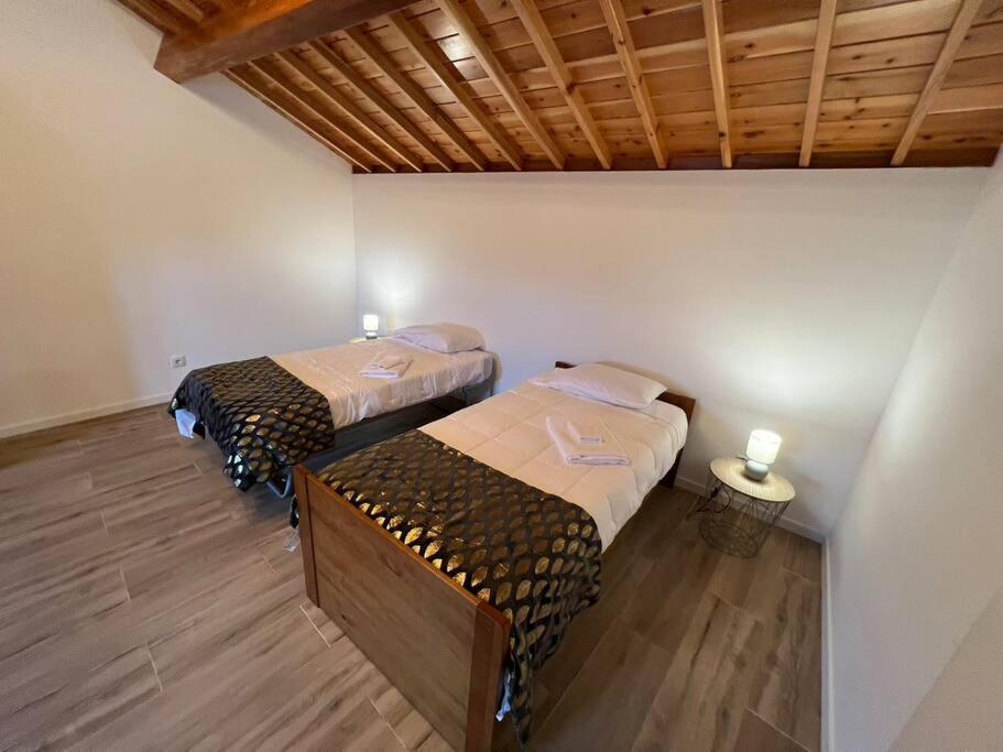 a room with two beds and a wooden ceiling at Casa do Avô Fernando in Agualva