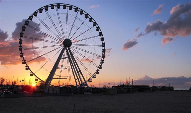 a ferris wheel with the sunset in the background at Appartamento fronte porto in Alghero