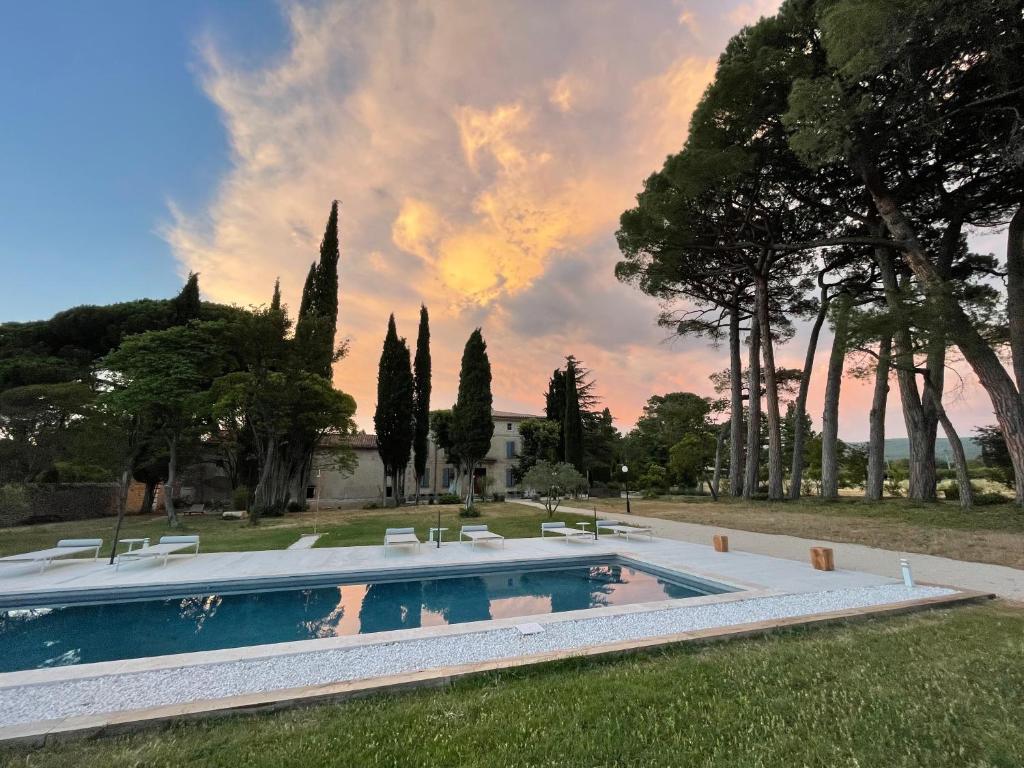 a swimming pool in a yard with trees and a sky at La Pavoyère in Mormoiron