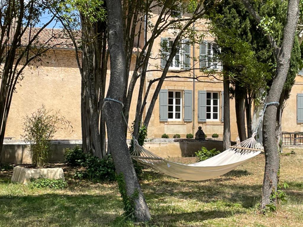 a hammock in front of a house with trees at La Pavoyère in Mormoiron