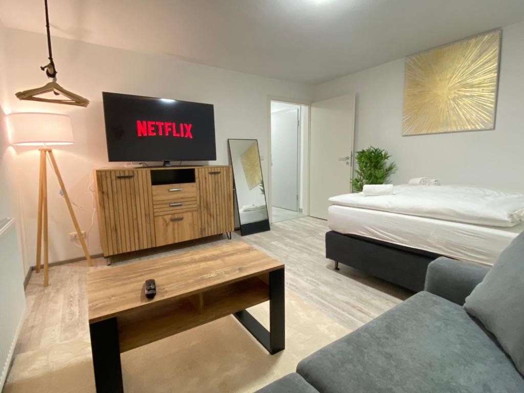 een woonkamer met een televisie en een bed bij LUXOMES: Design Apartment - private Parking - 4 People in Ingolstadt