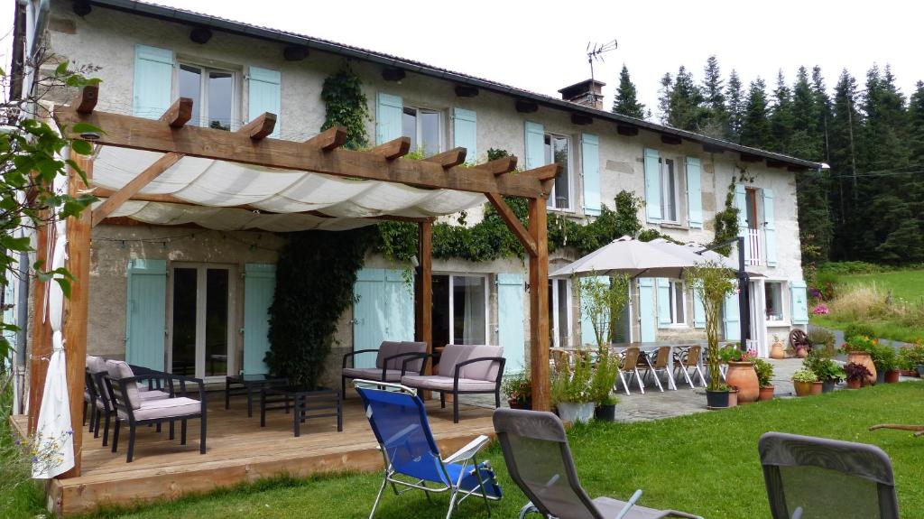 a house with a deck and chairs in the yard at La ferme du Garnasson- chambre Cassis in Doranges