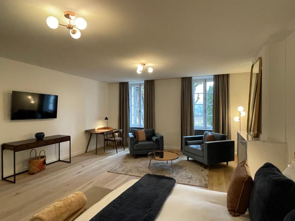 a living room with a couch and chairs and a tv at La Pavoyère in Mormoiron