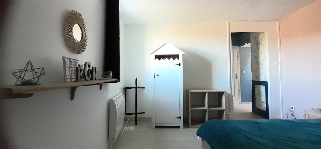 een slaapkamer met een bed en een spiegel aan de muur bij Chambre esprit 'plage' dans longère chez Stéphanie près circuit Mans in Marigné-Laillé