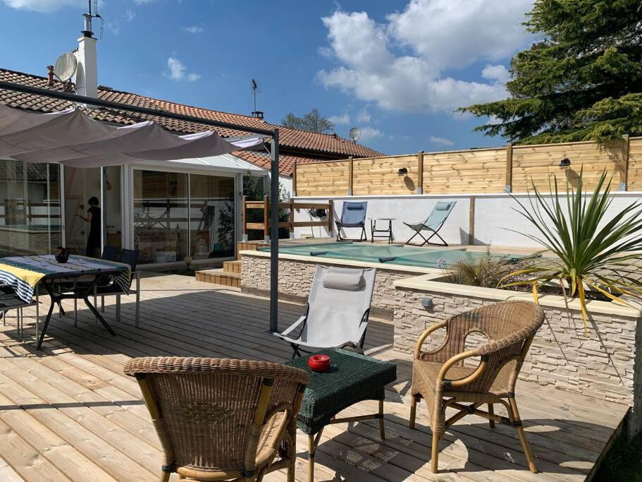 un patio con mesa, sillas y piscina en La Maison des Jardins en Naujac-sur-Mer