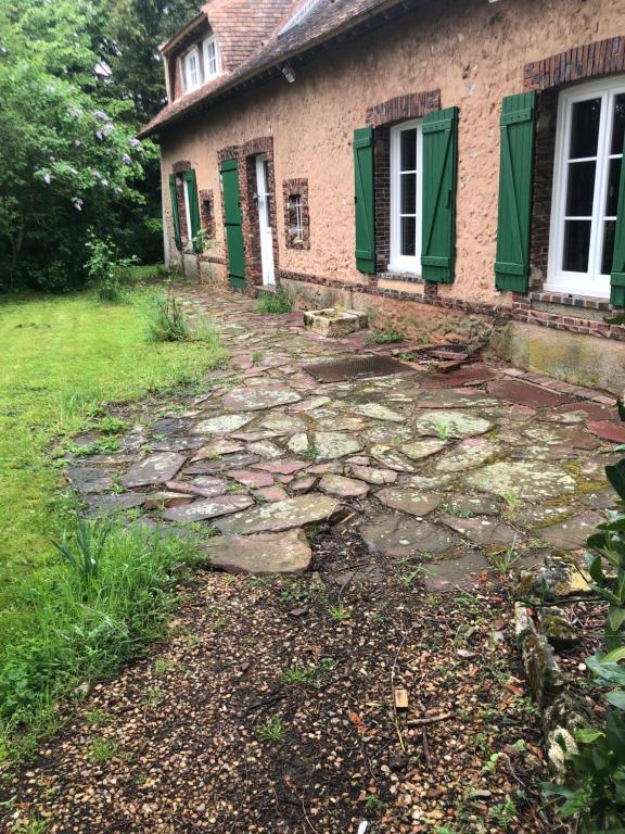 un camino de piedra que conduce a una casa con persianas verdes en Grande chambre avec salle de bain et WC privés, en Pontgouin