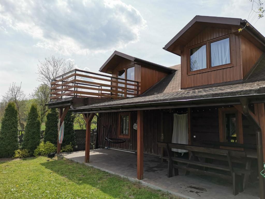 Cette maison en bois dispose d'une terrasse couverte et d'un balcon. dans l'établissement Apartament nad Zalewem, à Biszcza