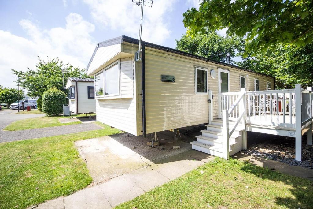 a yellow and white tiny house with a porch at Caravan With Decking At Highfield Grange In Essex Ref 26452ba in Clacton-on-Sea