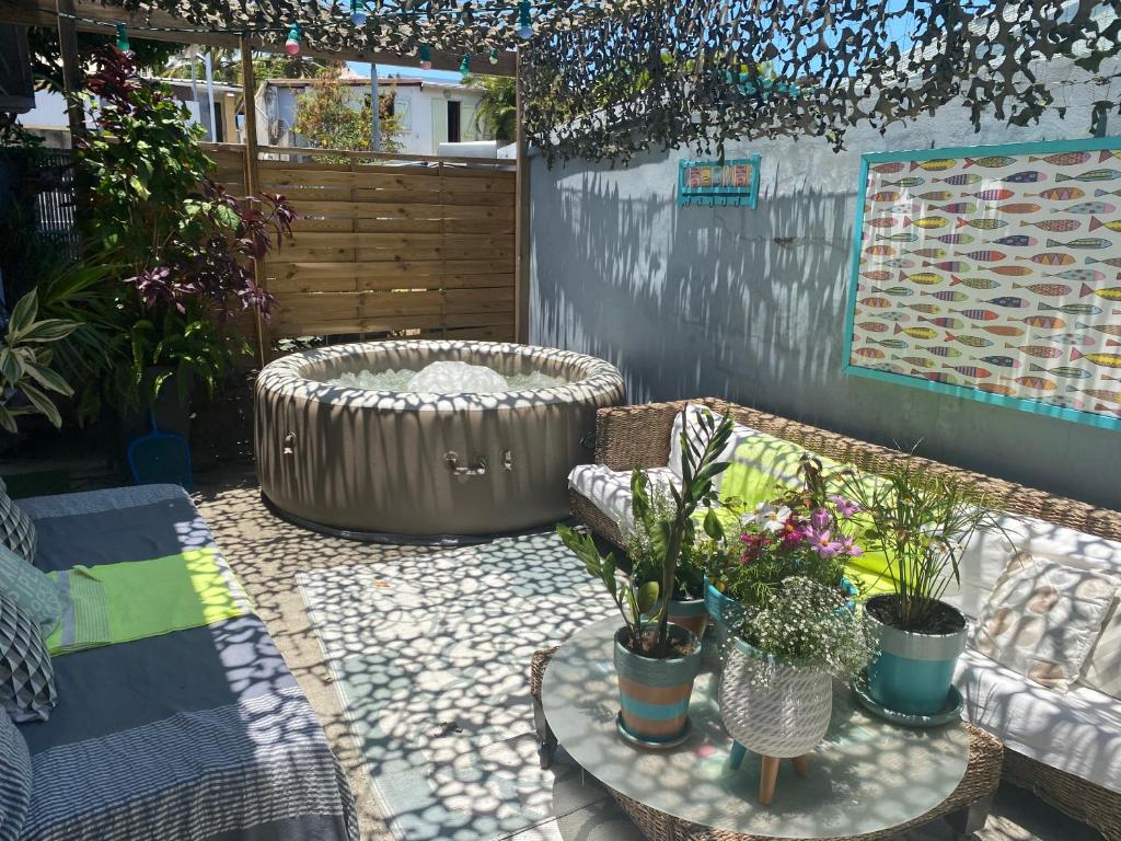 une terrasse avec une baignoire et des plantes en pot dans l'établissement La kaze manguiers, à L'Étang-Salé
