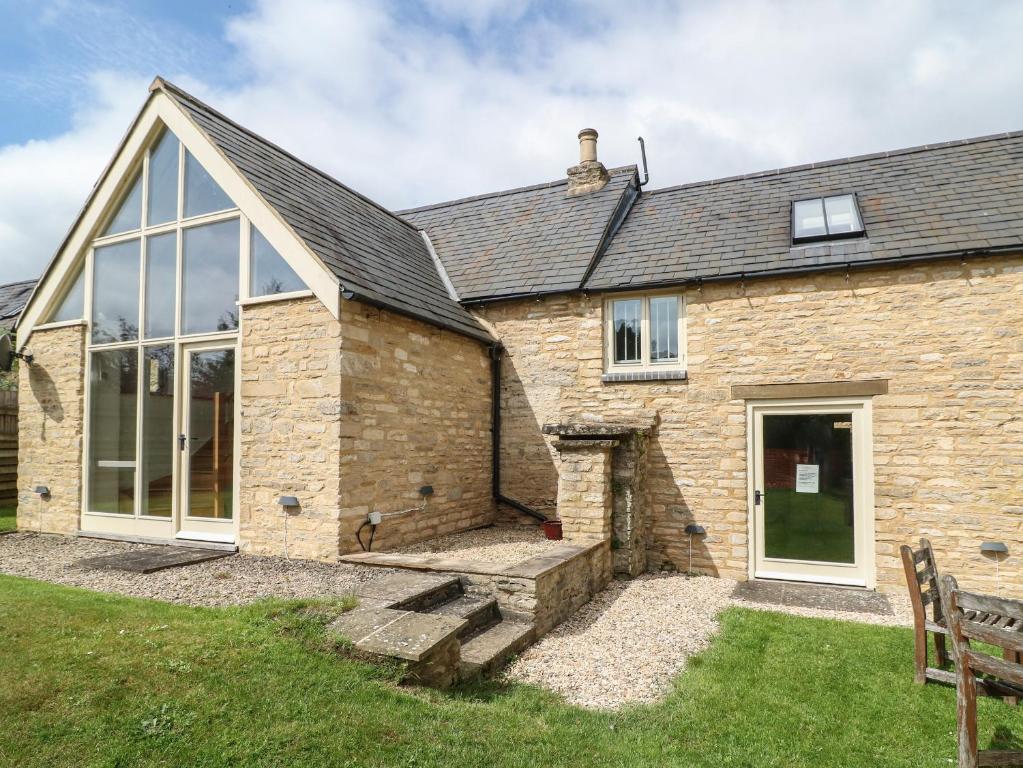 an external view of a stone house with a bench at Malt Barn in Burford