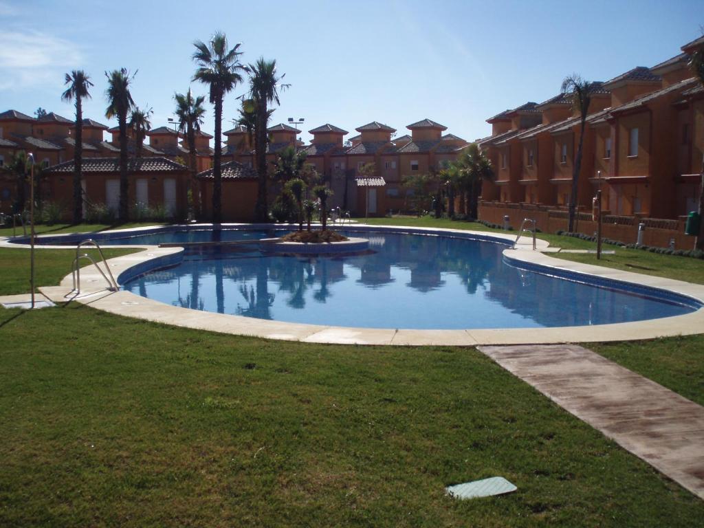 una gran piscina en un patio con palmeras en Pinares de Lepe, en Huelva