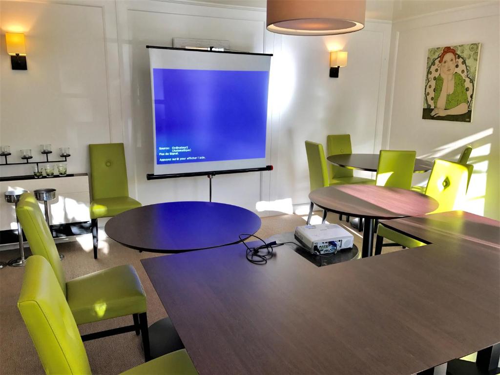 a meeting room with tables and a projection screen at Hôtel-Restaurant La Mascotte in La Baule