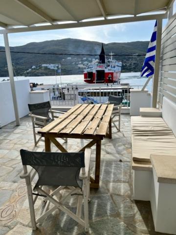 - une table et des chaises en bois sur une terrasse avec un bateau dans l'établissement Captain's Port Studio, à Gavrio
