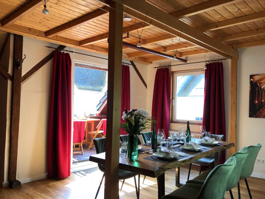 ein Esszimmer mit einem langen Tisch und roten Vorhängen in der Unterkunft Ferienhaus-Am-Alten-Stadttor in Ediger-Eller