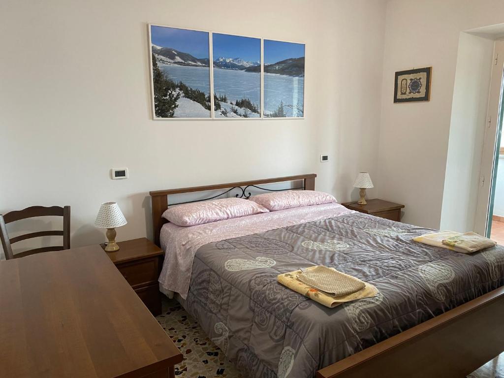 a bedroom with a bed with a table and a picture on the wall at Casa vacanze Lago di Campotosto in Campotosto