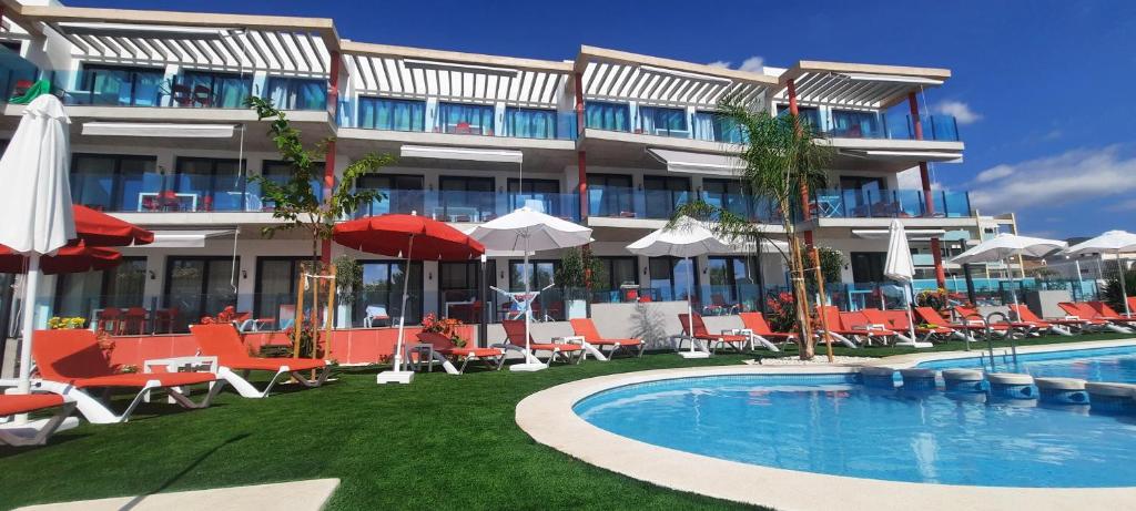 a hotel with a swimming pool and chairs and a building at AZAHAR BEACH Red Apartments & Spa in Alcossebre