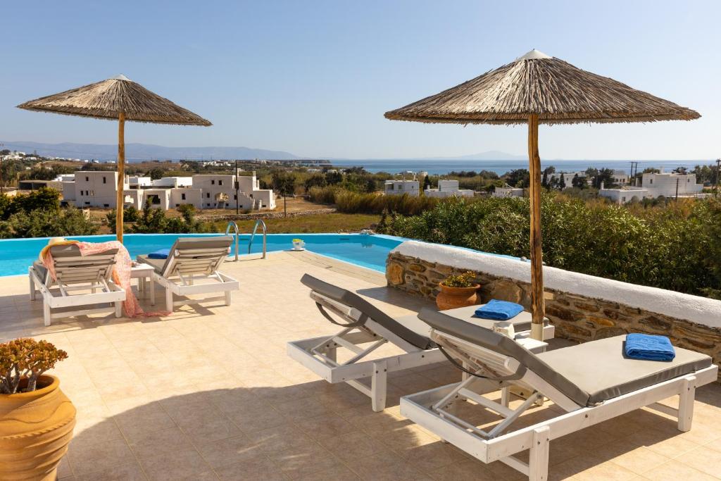 a patio with chairs and umbrellas and a swimming pool at Crystal Villa III in Chrissi Akti