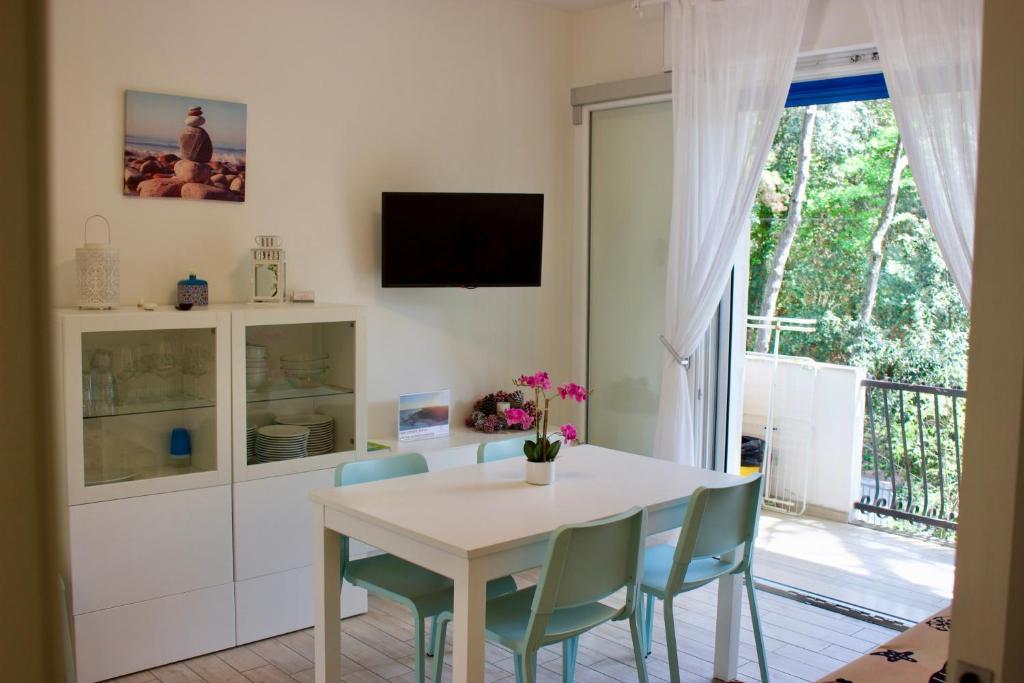 una sala da pranzo con tavolo e sedie bianchi di Villa Antonietta 3, tra pineta e mare a Bibione