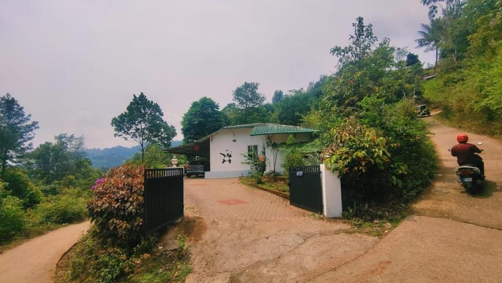 un hombre en una motocicleta por un camino de tierra en Westernghats Homestay en Madikeri