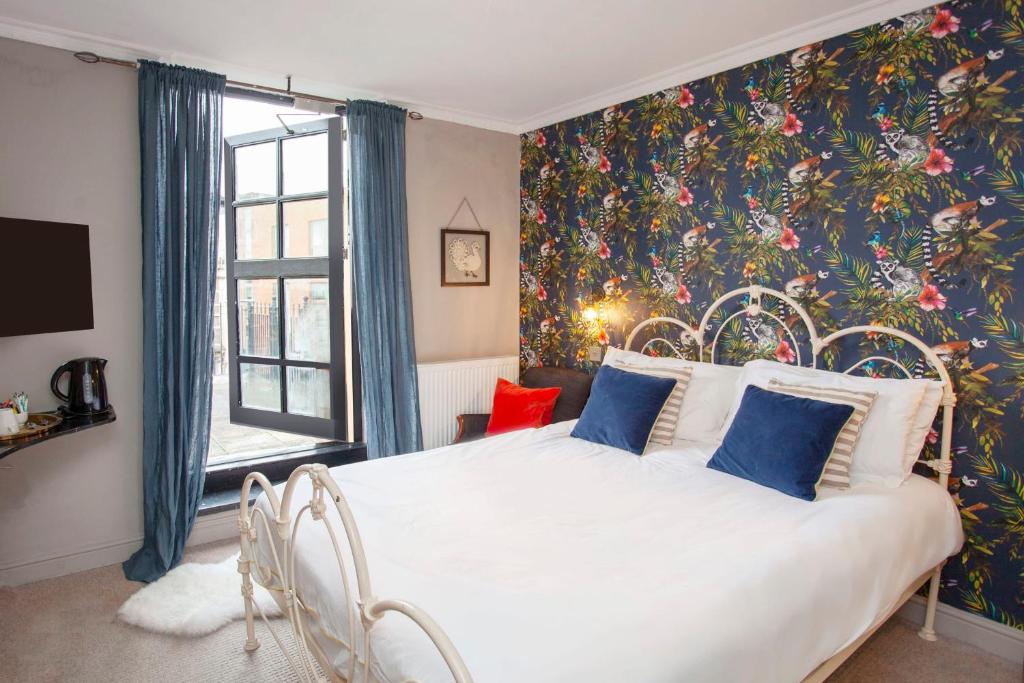 um quarto com uma cama branca e papel de parede floral em higgihaus #5 Room 6 Monday - Friday em Cardiff