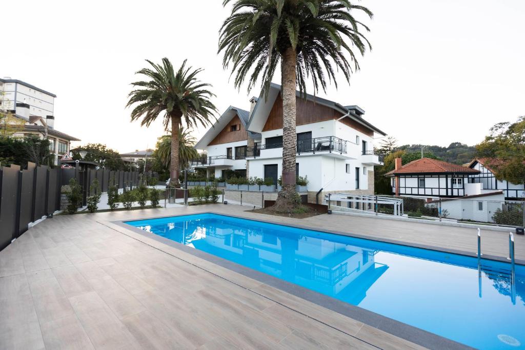 a swimming pool in front of a house with palm trees at Villa Carmen by Basquelidays in Hondarribia