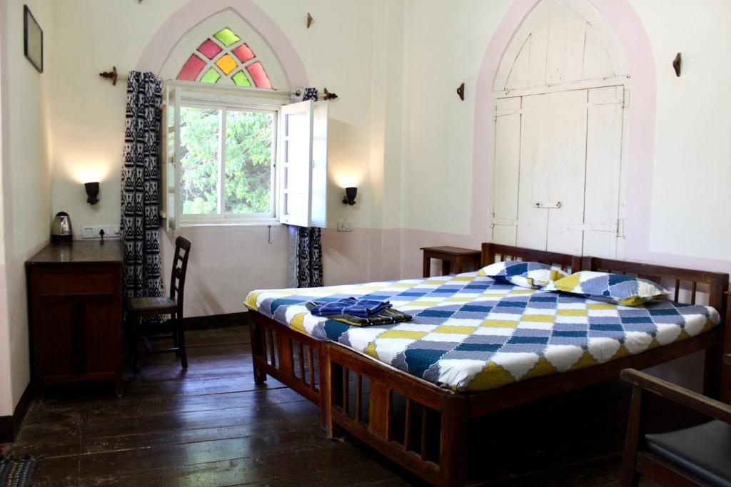 a bedroom with a bed and a window and a table at Royal Phoenix Inn in Panaji