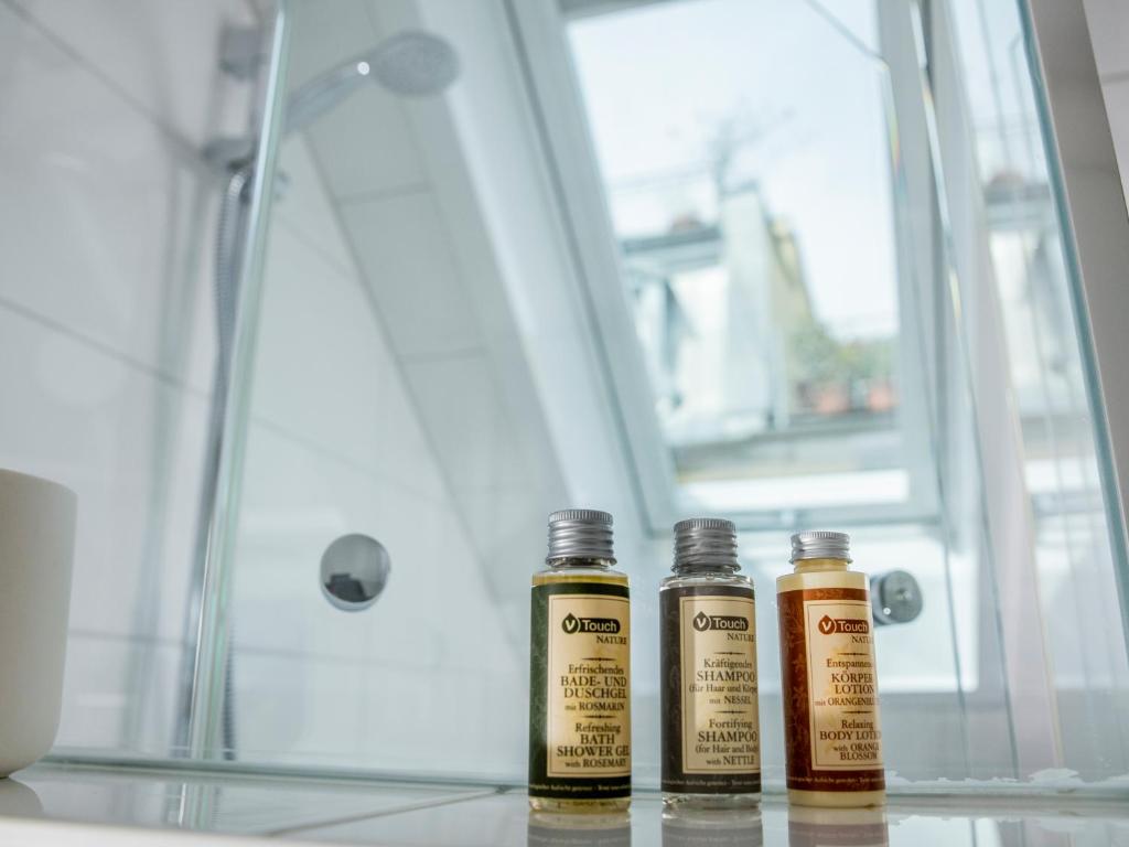 three bottles of oils sitting on a shelf in a shower at Haus Triflinger in Lindau