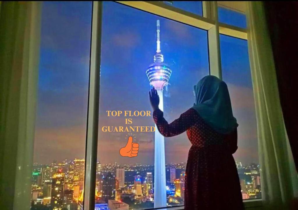 a woman standing in front of a window holding up a light bulb at Vortex Suites at KLCC Area in Kuala Lumpur