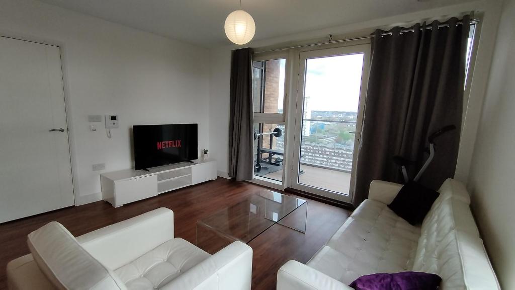 ein Wohnzimmer mit einem weißen Sofa und einem TV in der Unterkunft Riverview Amazing 2Bed 2Bath Apt wParking Sleeps 6 Comfortably in London
