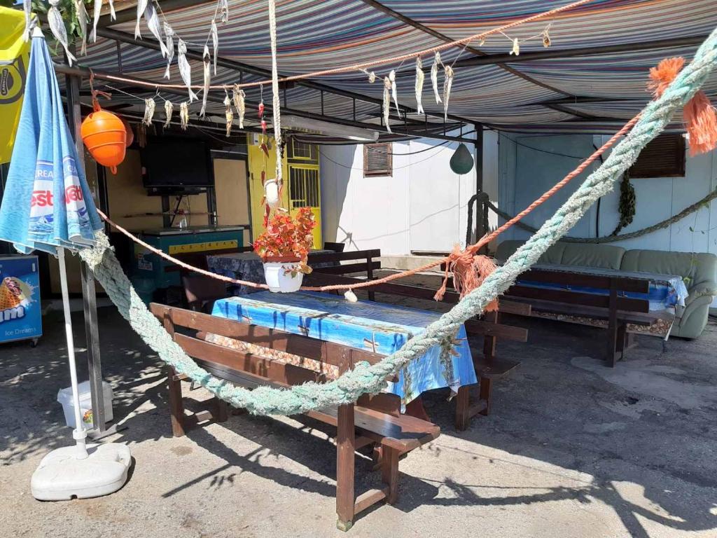 a hammock hanging from a tent with a table and benches at Бунгала,, Металик,, Шкорпиловци in Shkorpilovtsi