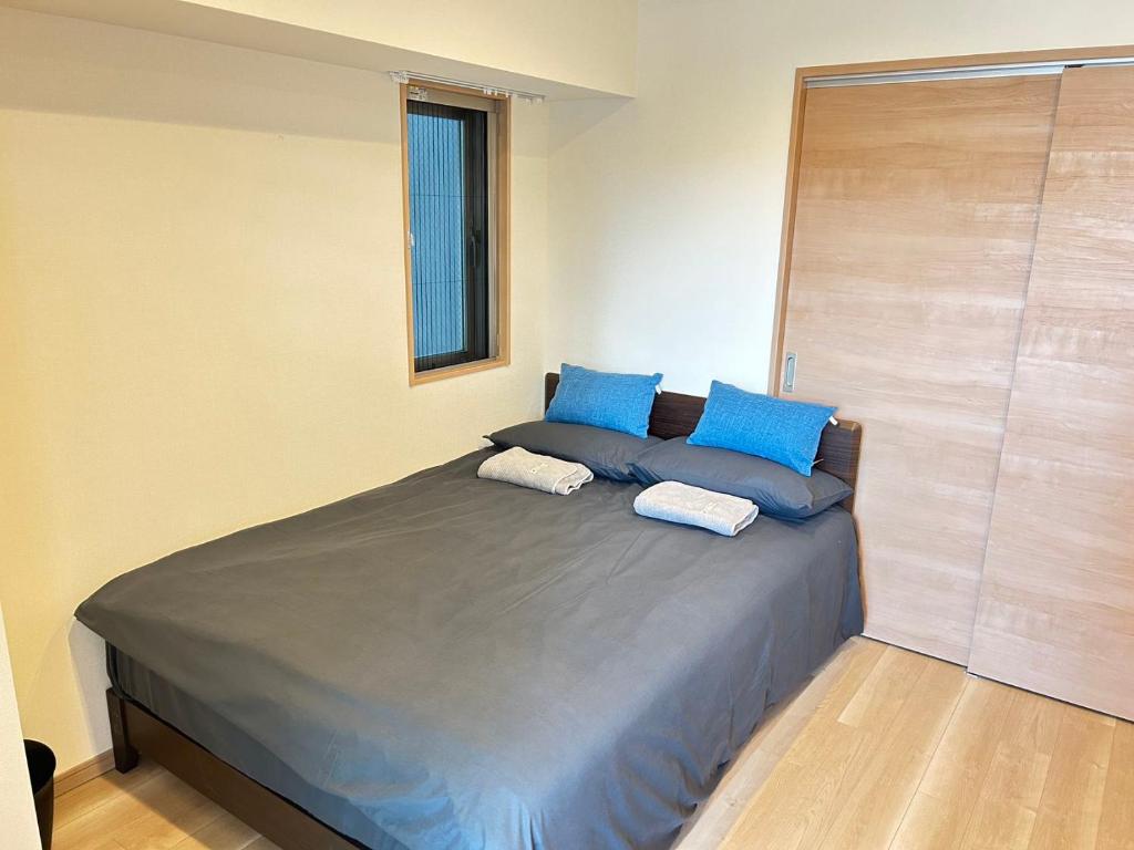 łóżko w pokoju z niebieskimi poduszkami w obiekcie 大阪谷町橋の宿 w Osace