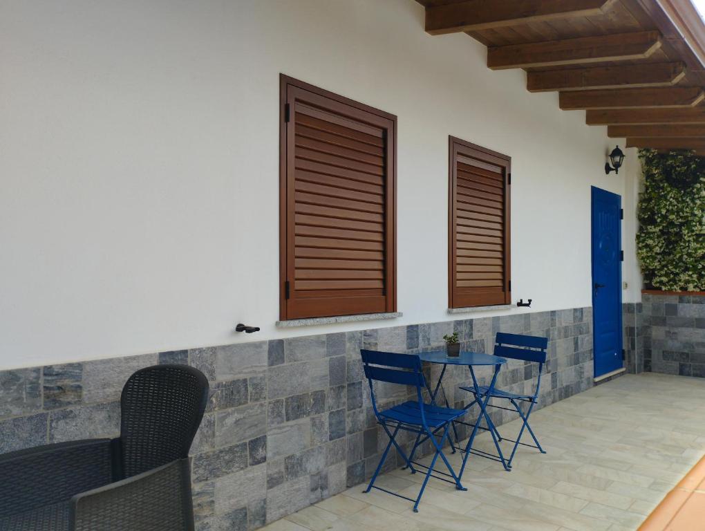 a patio with blue chairs and a table and windows at Affitta Camere Zio Peppe in San Teodoro